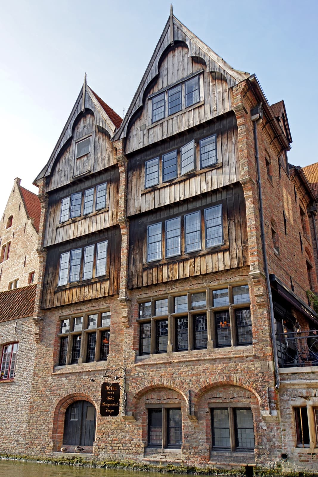 A tall half-timbered house with gables rising straight from a canal