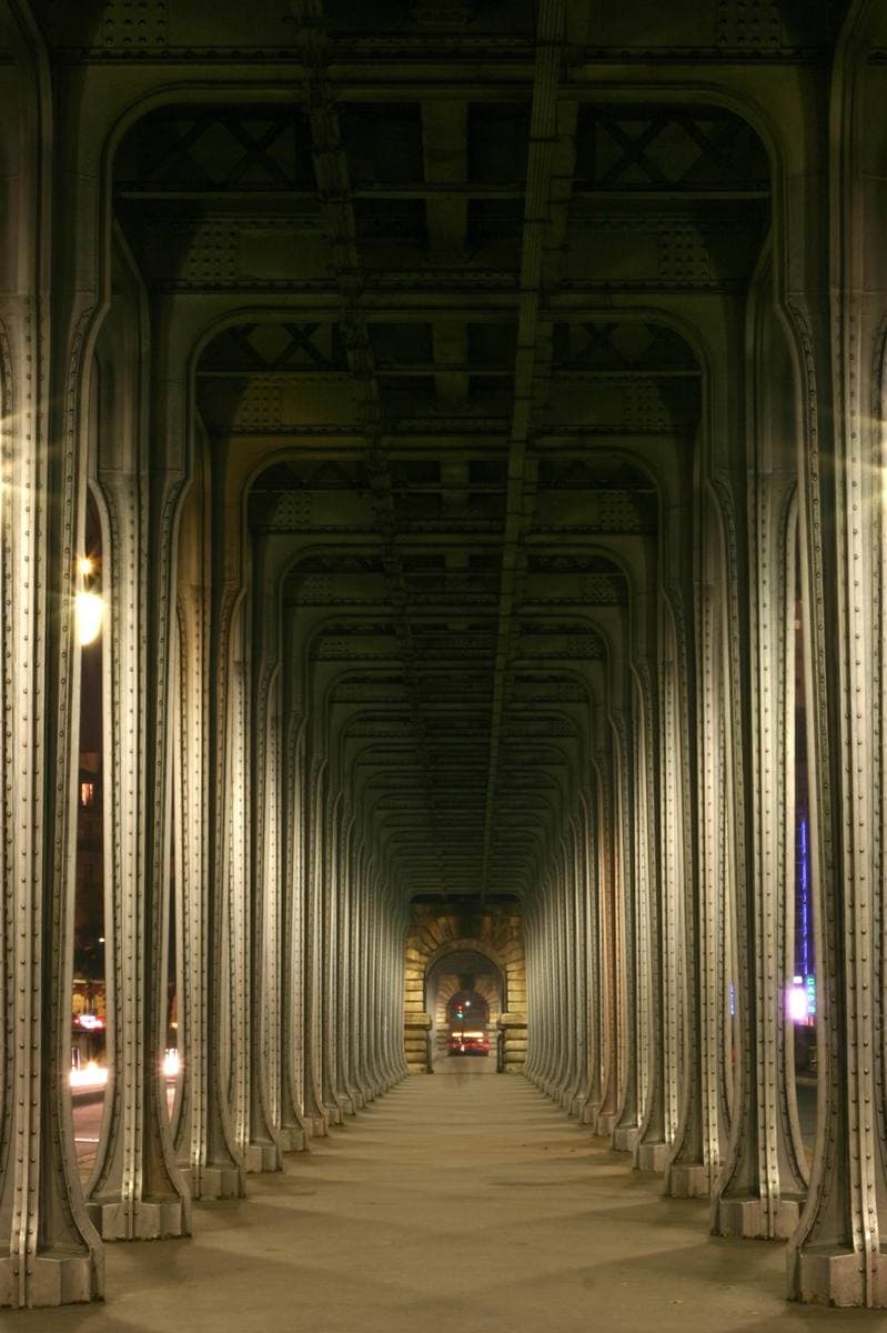 A long covered walkway between two rows of iron columns, receding to a point