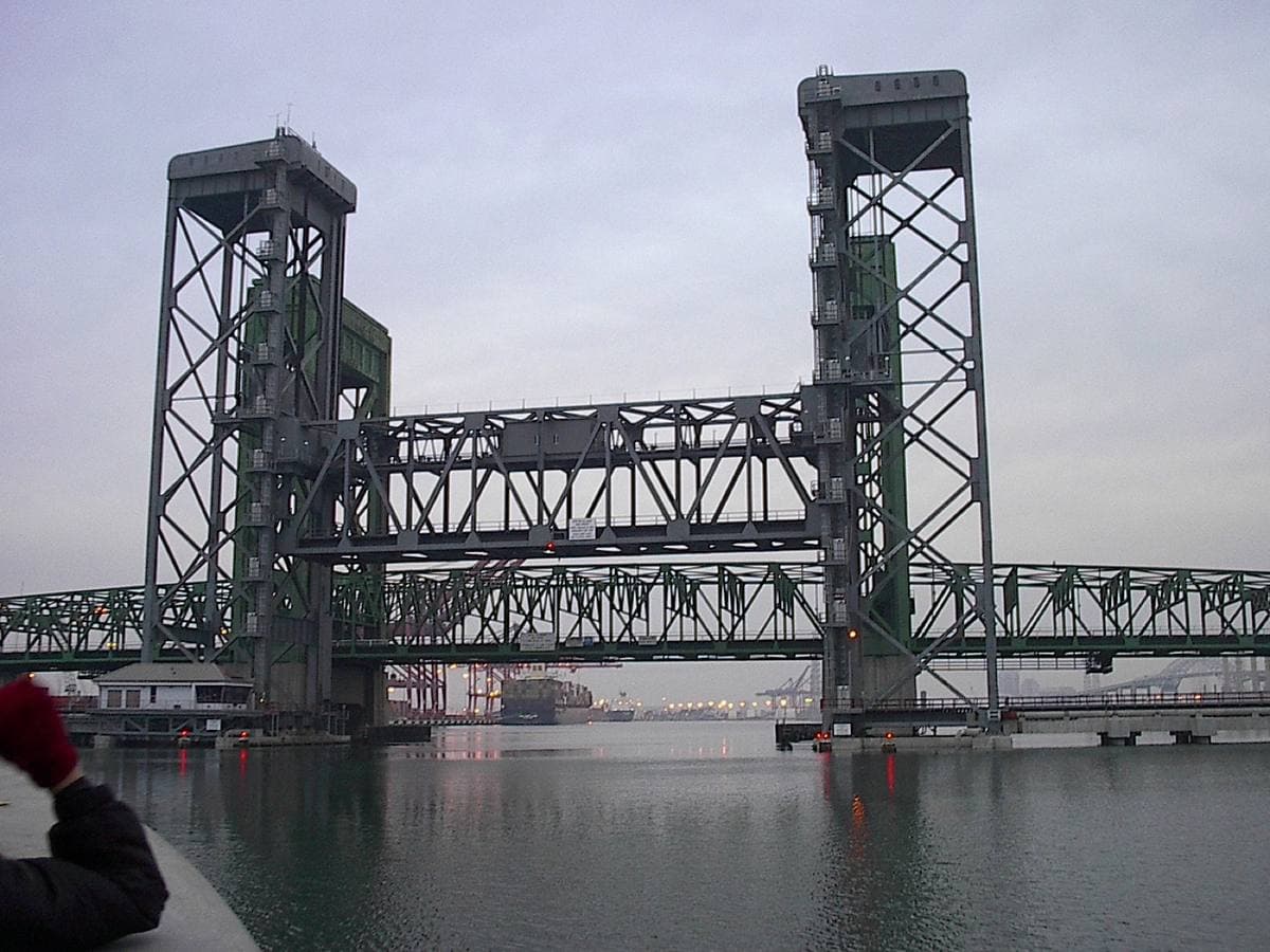 A steel lift bridge with two tall towers over grey water