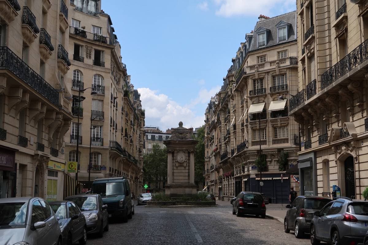 A small Paris square of stone apartment buildings around a column fountain