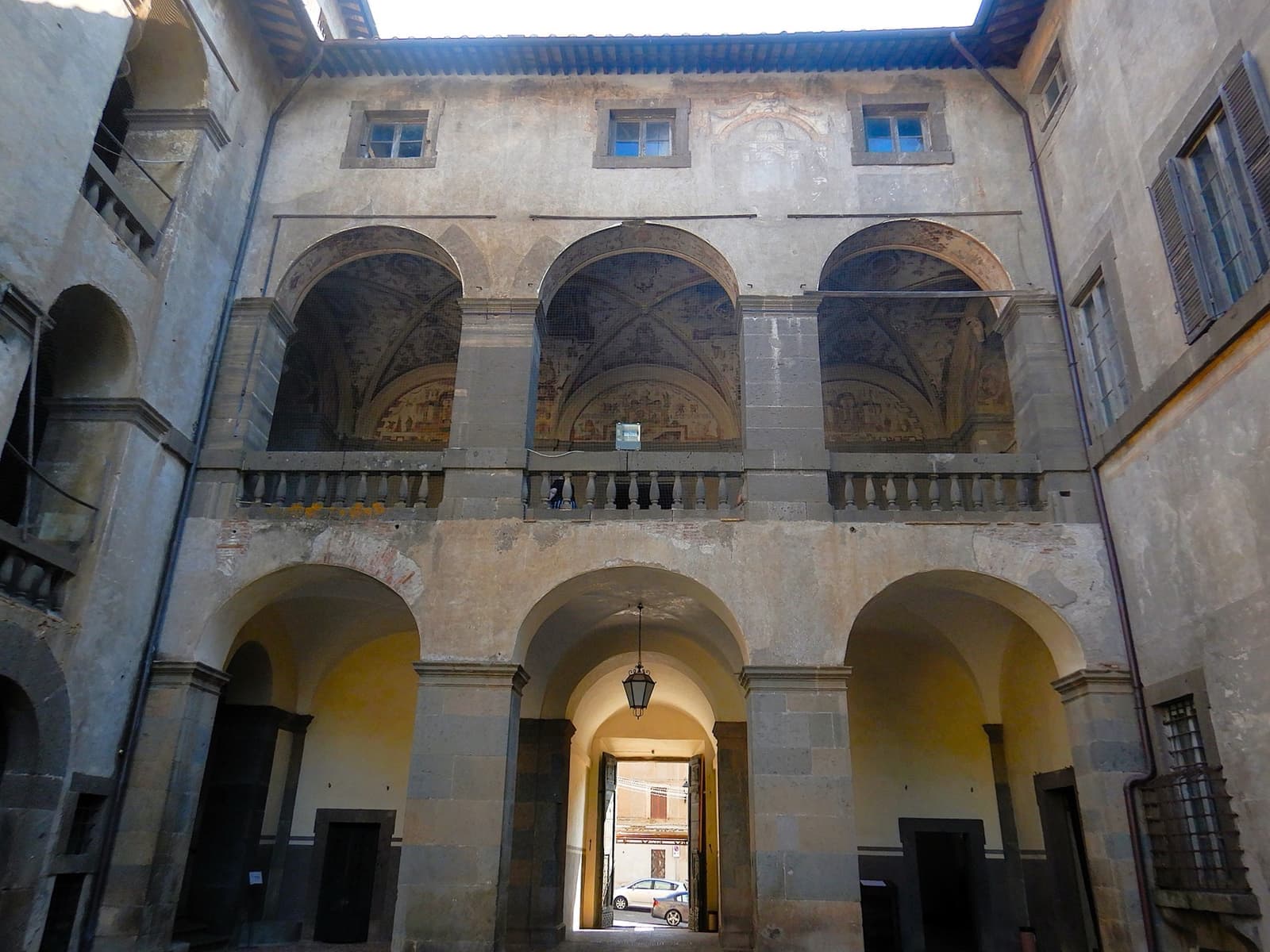 An arcaded stone courtyard with frescoed vaults
