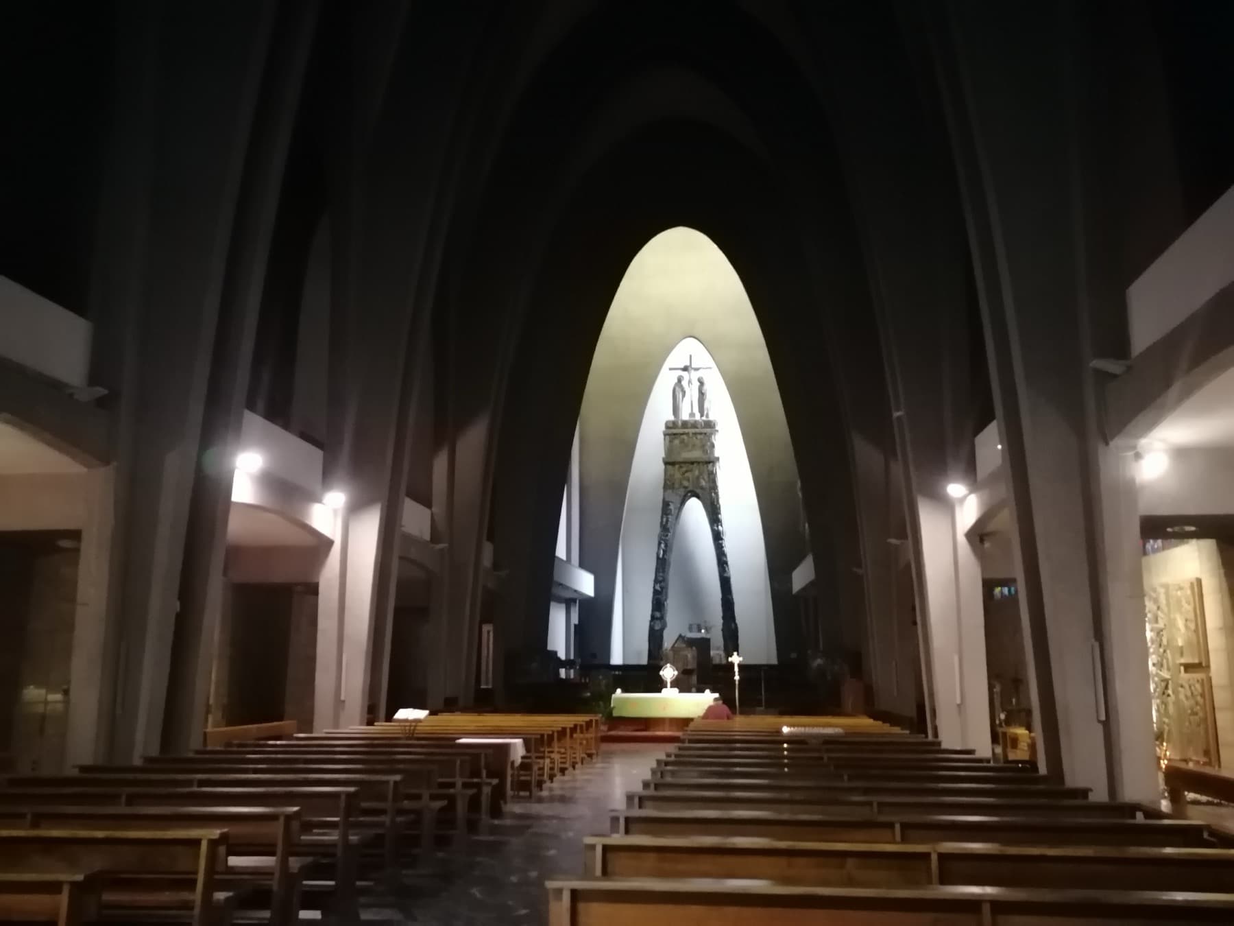 A tall pointed nave of concrete ribs leading to a lit apse