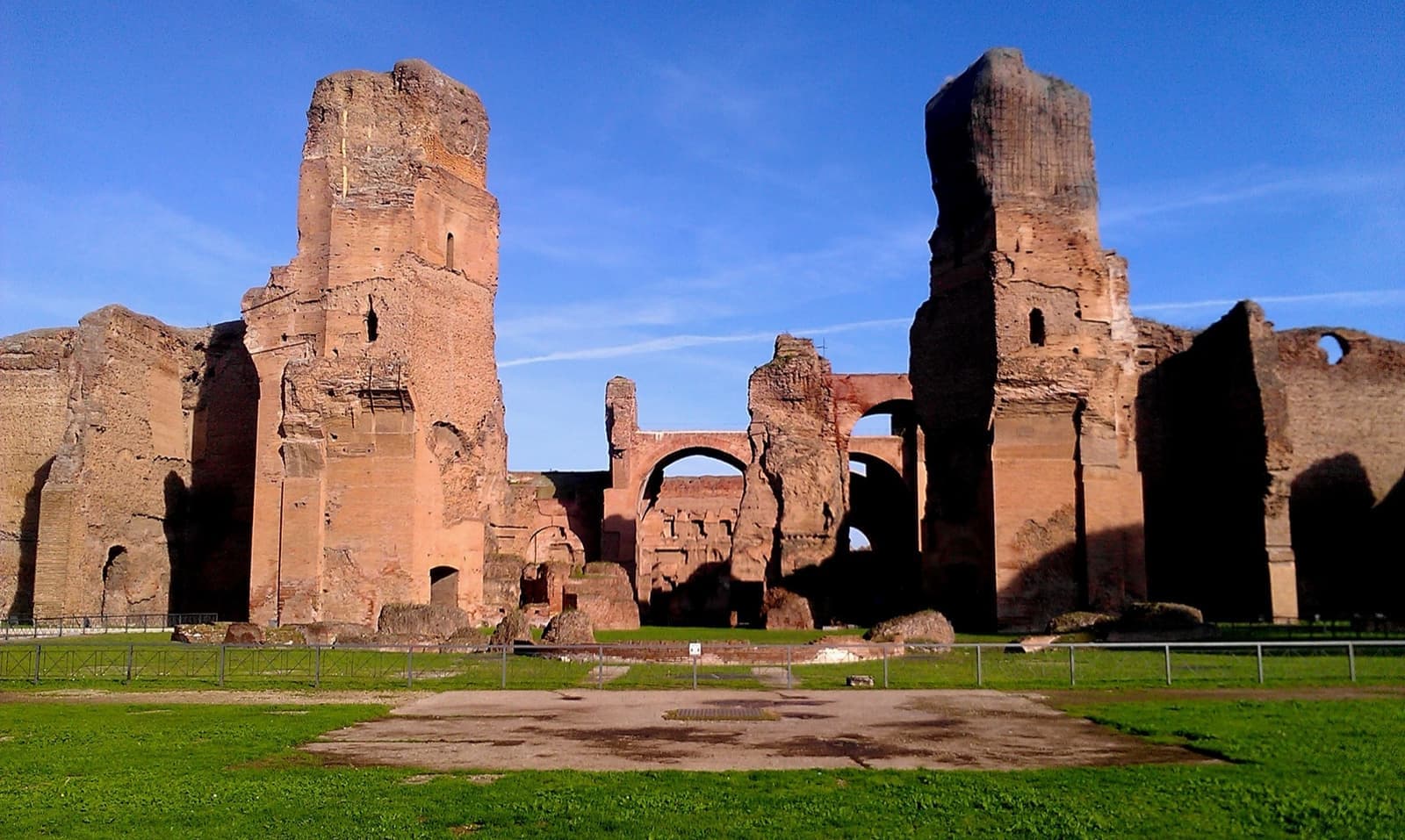 Tall brick ruins of the Roman baths against a blue sky