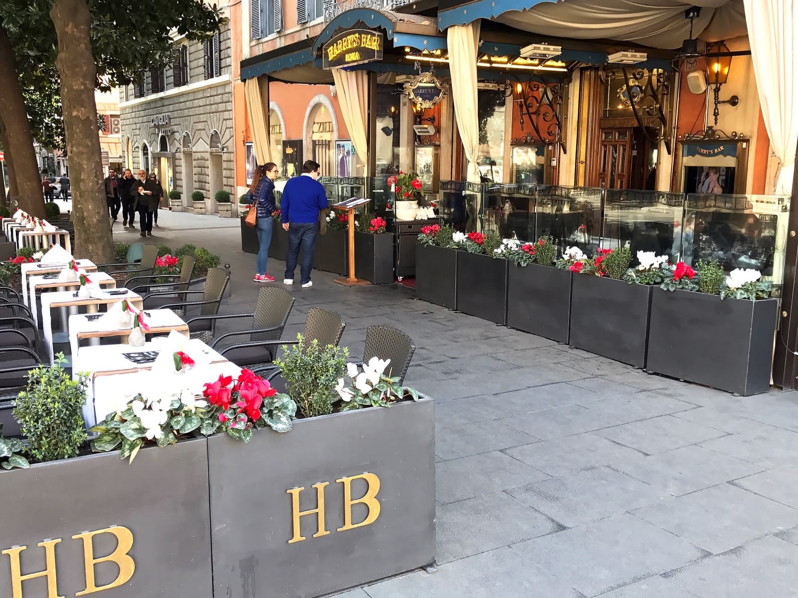 Café tables and flower boxes marked HB outside Harry’s Bar