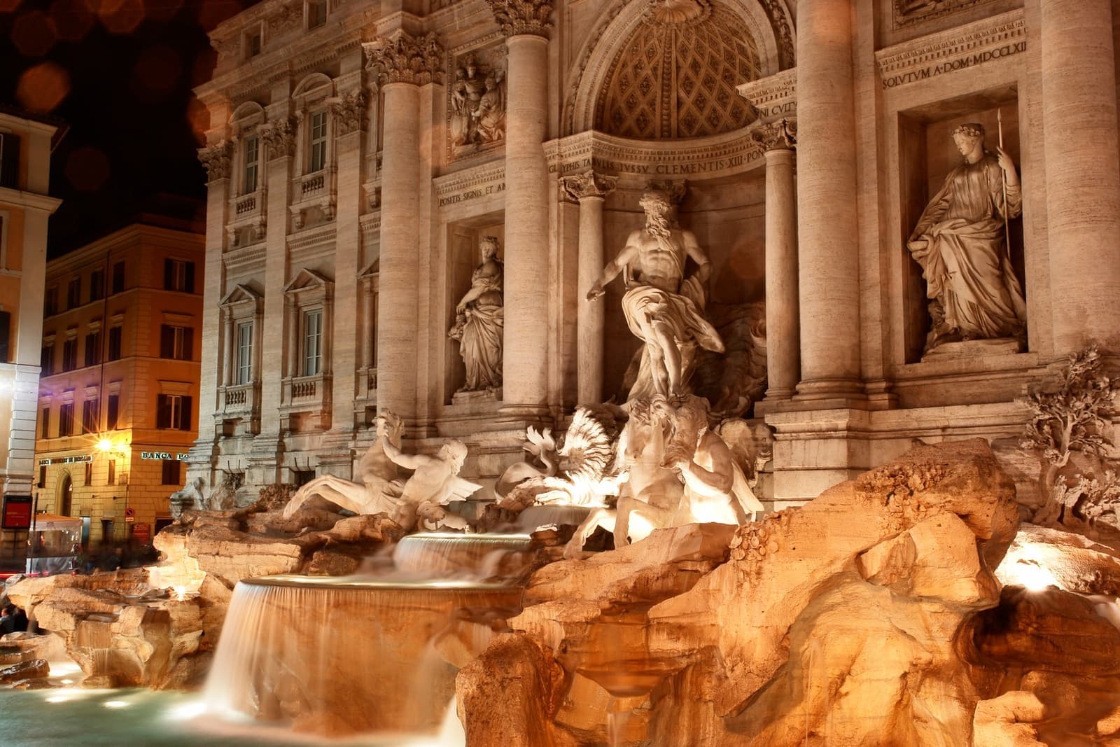Neptune and the tritons of the Trevi Fountain lit gold at night