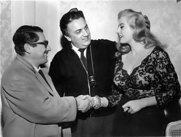 Fellini, between Ennio Flaiano and Anita Ekberg, shakes Flaiano’s hand
