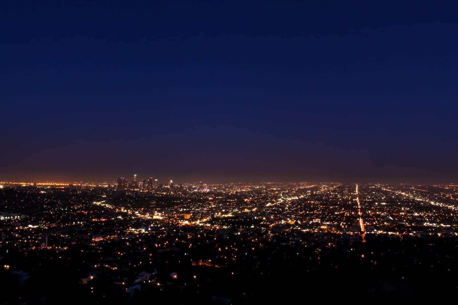 The lights of the Los Angeles grid at blue hour under a wide darkening sky