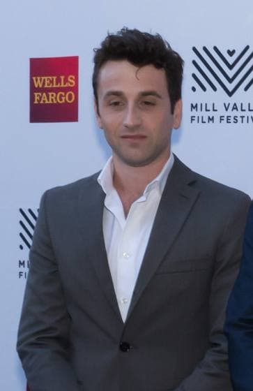 Justin Hurwitz in a grey suit and open-necked white shirt
