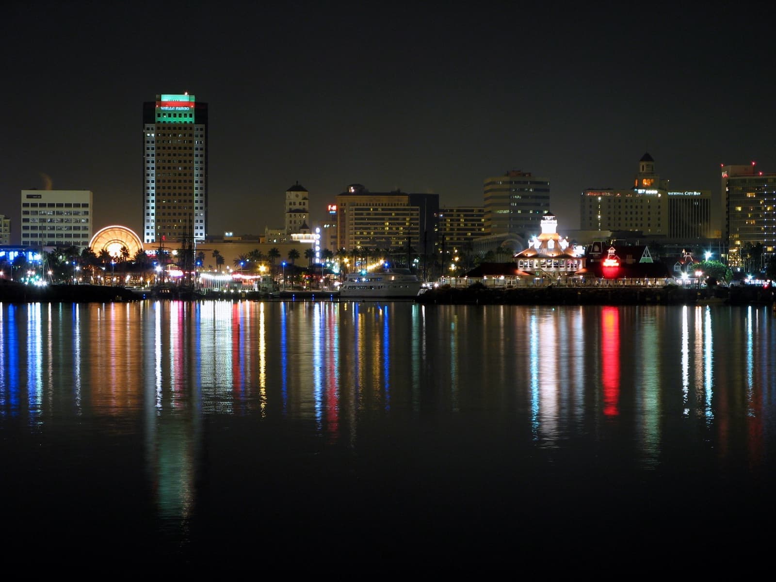 The lit towers and waterfront of Downtown Long Beach at night, reflected in dark water