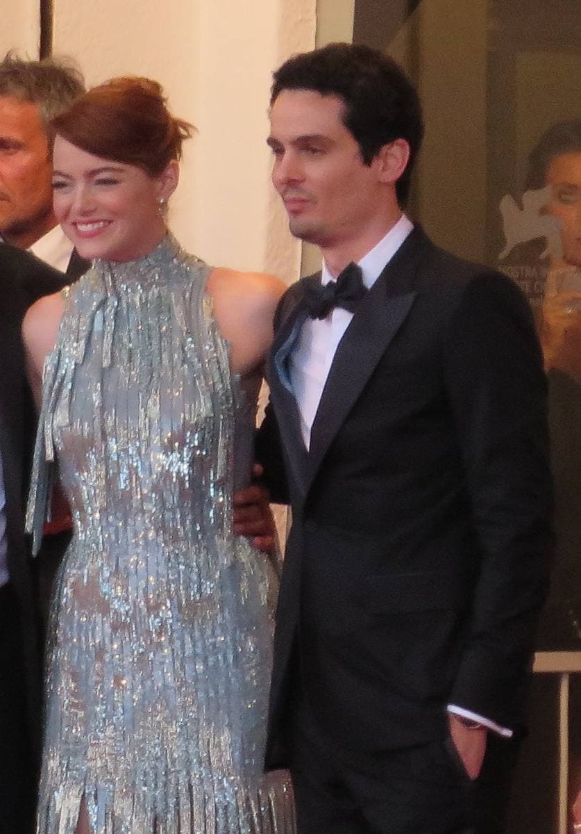 Emma Stone in a silver fringed gown beside Damien Chazelle in a dinner jacket