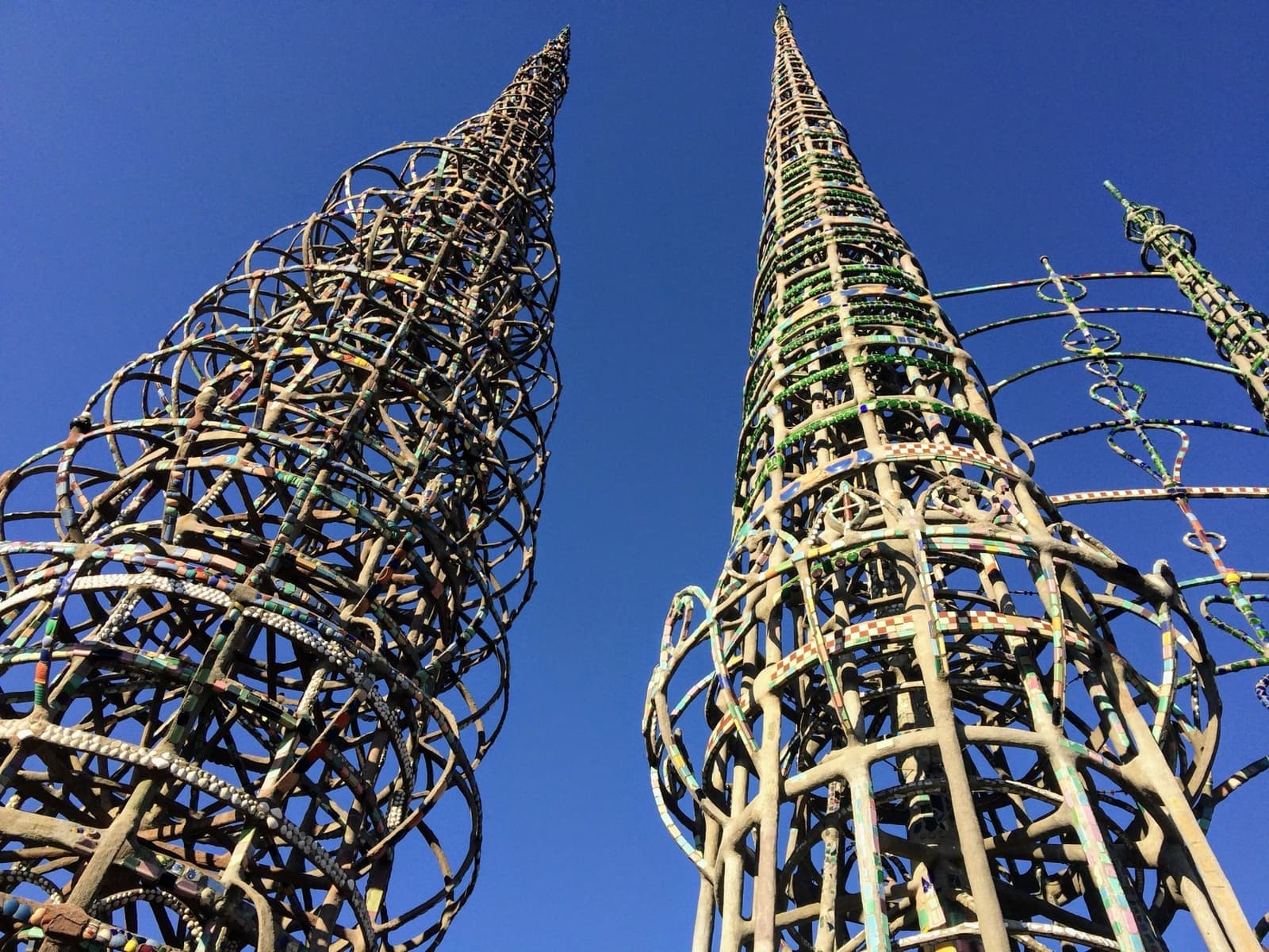 Two lace-like spires of the Watts Towers against a deep blue sky