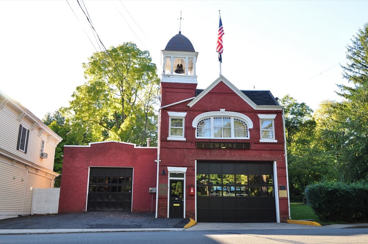 A brick firehouse with arched doors on a village street