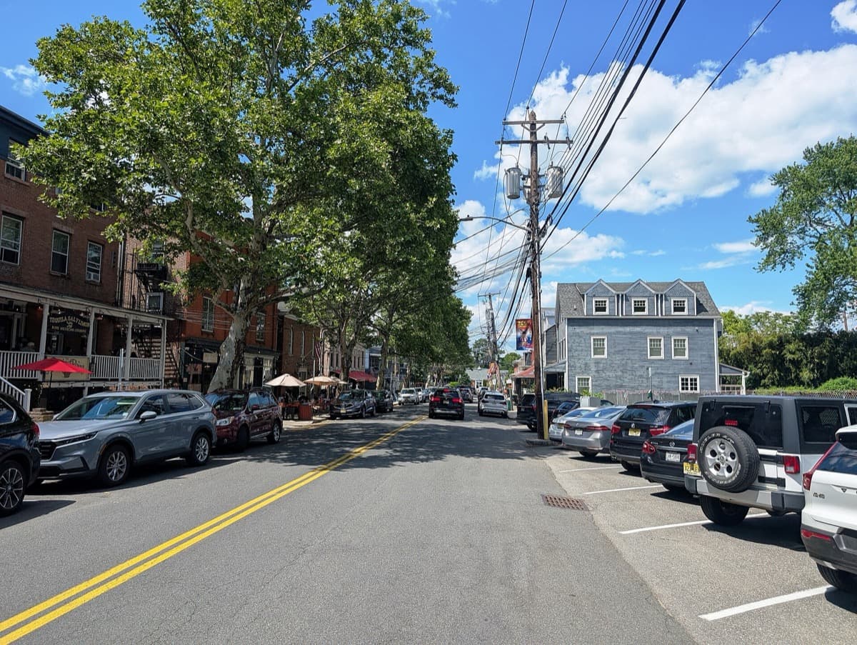 A village street lined with shops and parked cars in summer