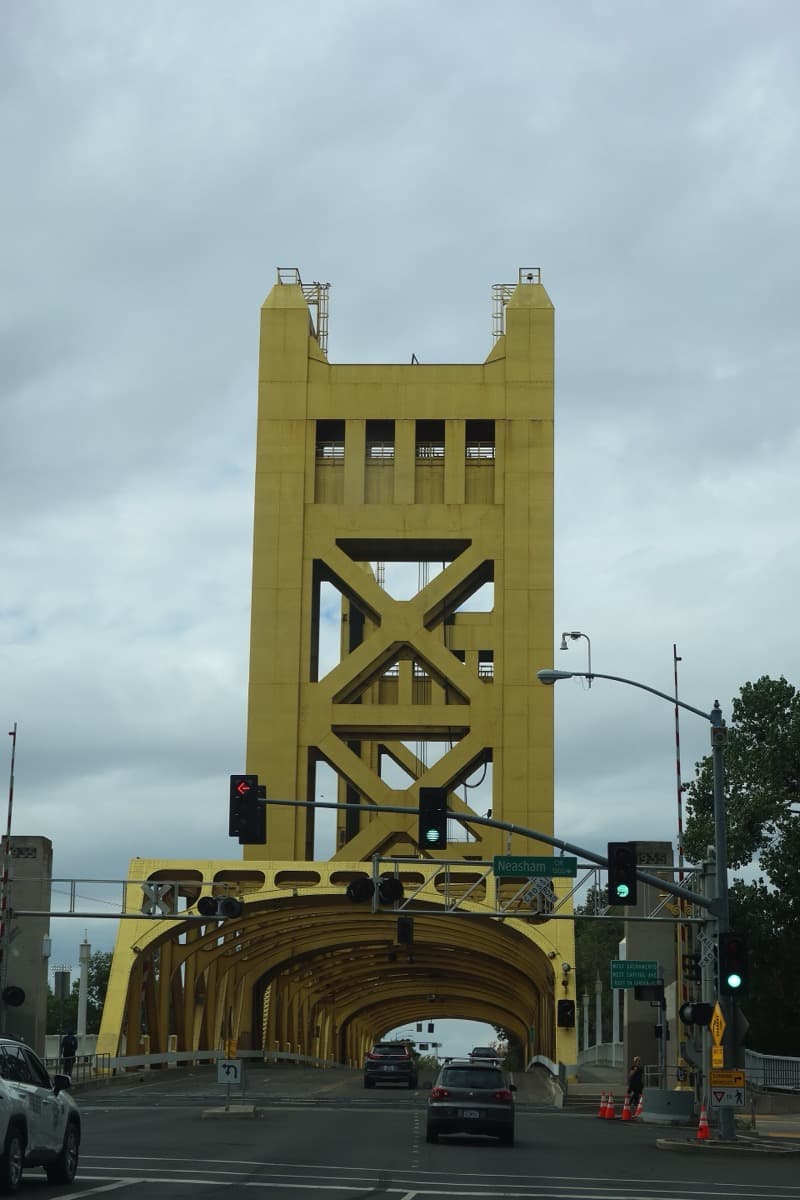 A gold-painted vertical-lift bridge with two tall towers over a river