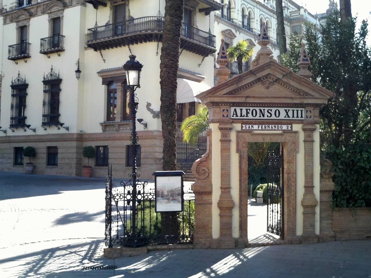 The gateway of a white hotel with ironwork balconies and a tiled sign