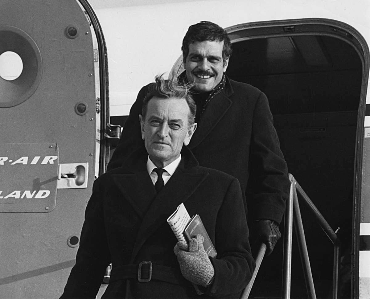 David Lean and Omar Sharif coming down the steps of a Kar-Air aircraft in winter coats