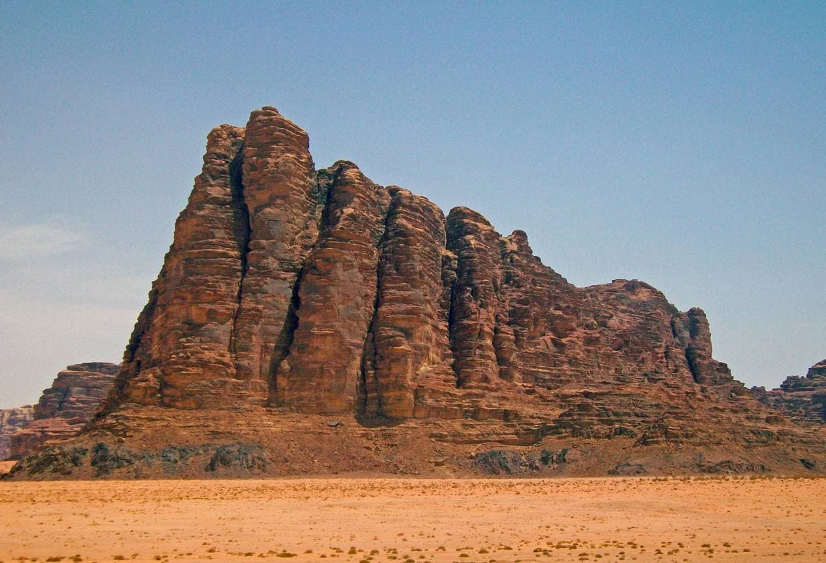 A huge fluted red sandstone mountain rising from the desert floor