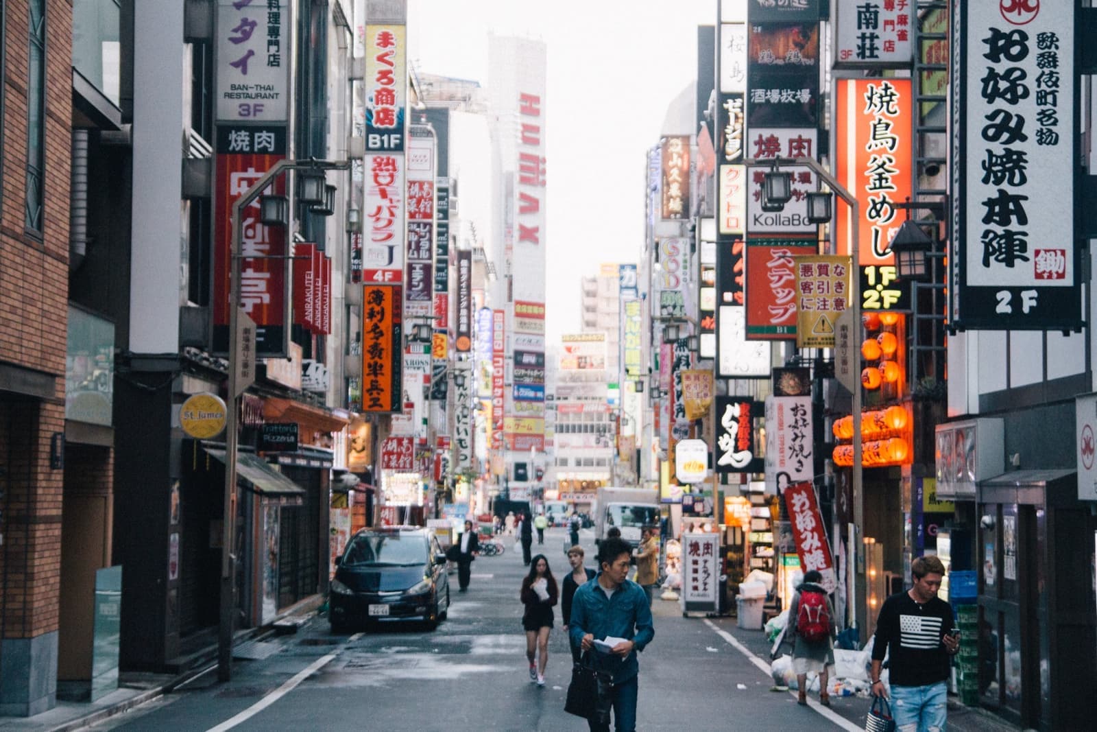 A narrow street hung with vertical shop and restaurant signs