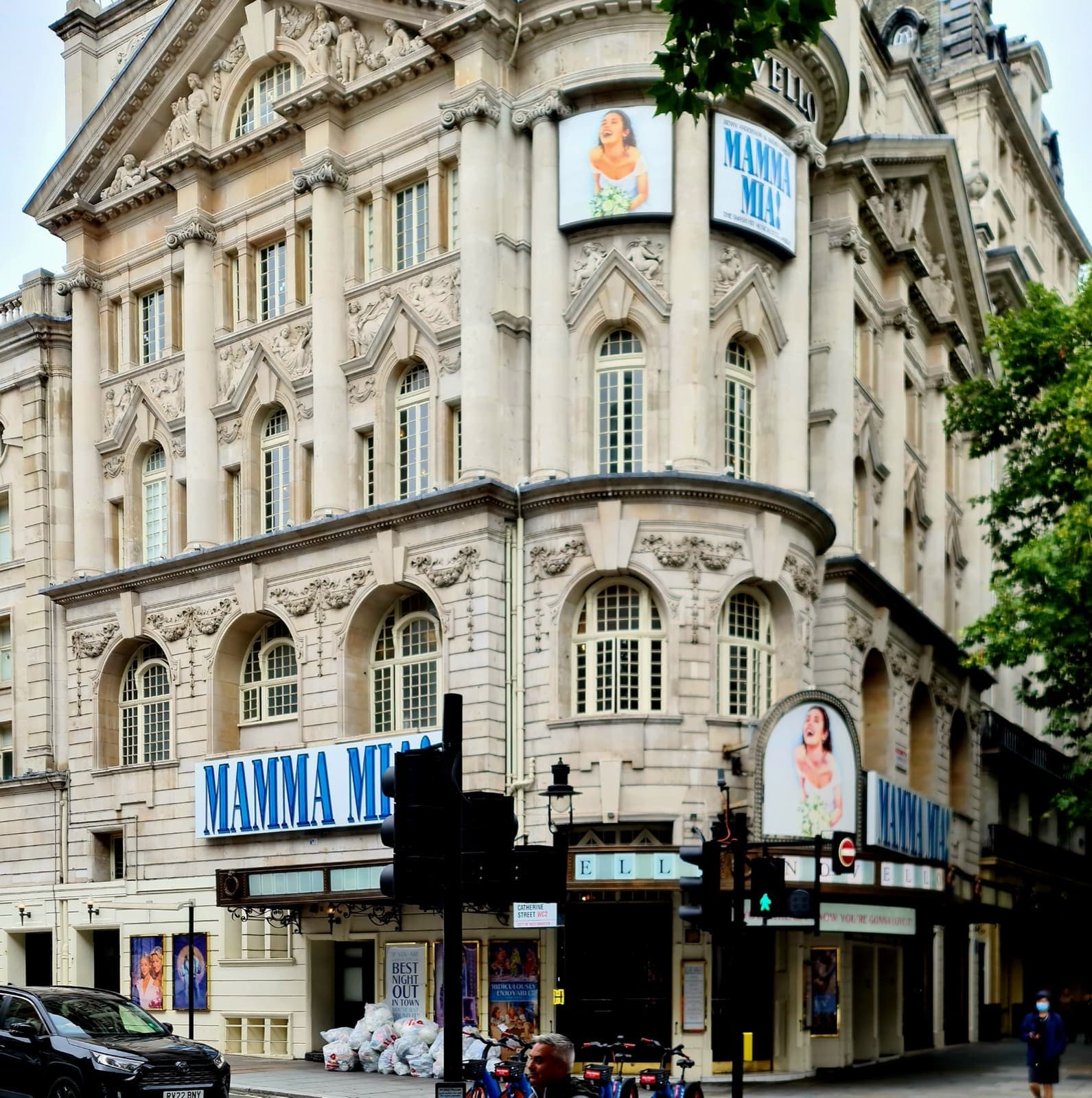 A grand stone theatre front on a street corner, with Mamma Mia! signs above the entrance