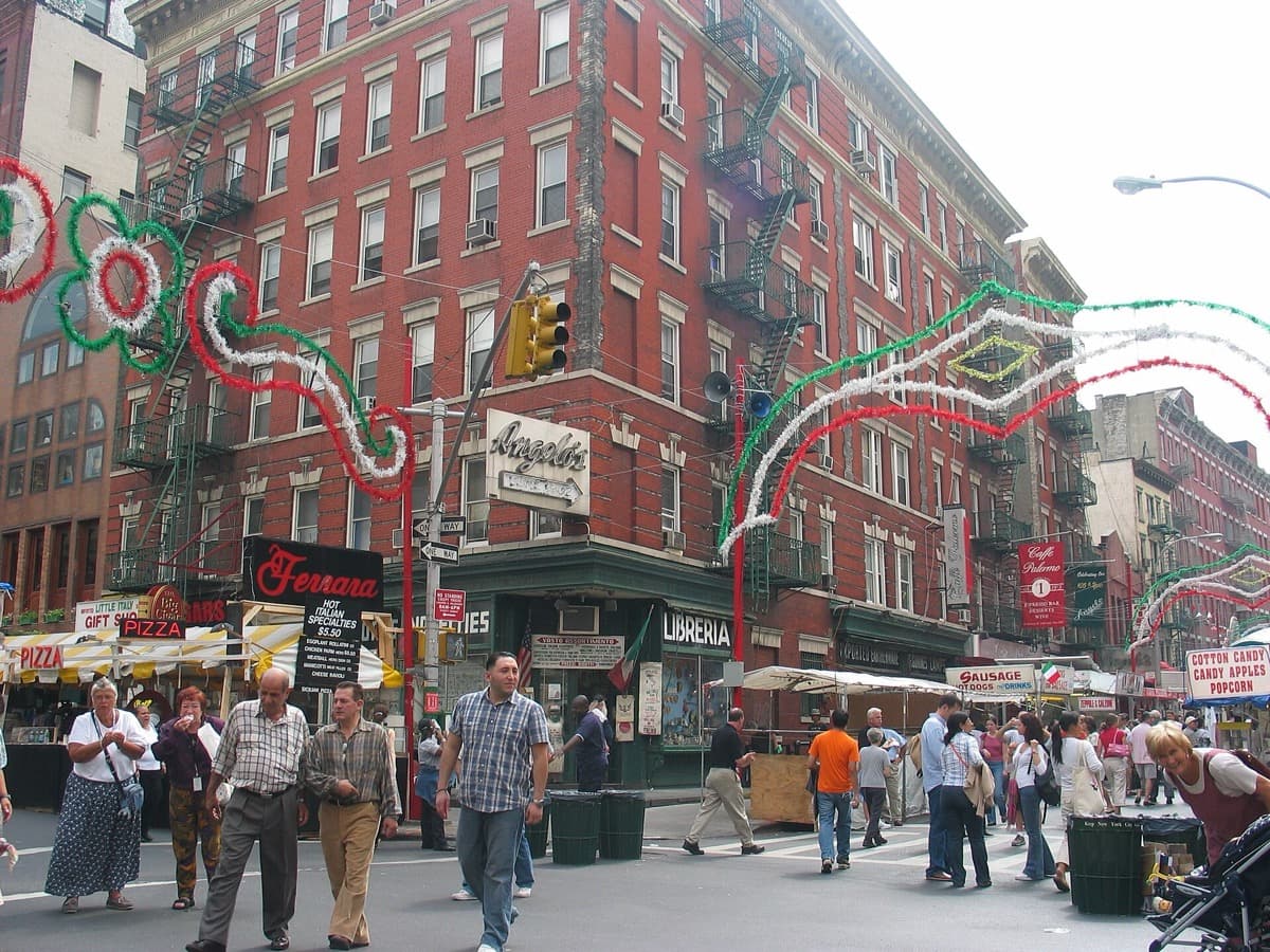 A crowded street lined with stalls and strings of festival lights