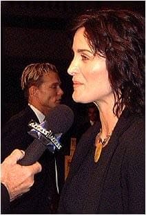 Carrie-Anne Moss in profile, talking into a microphone
