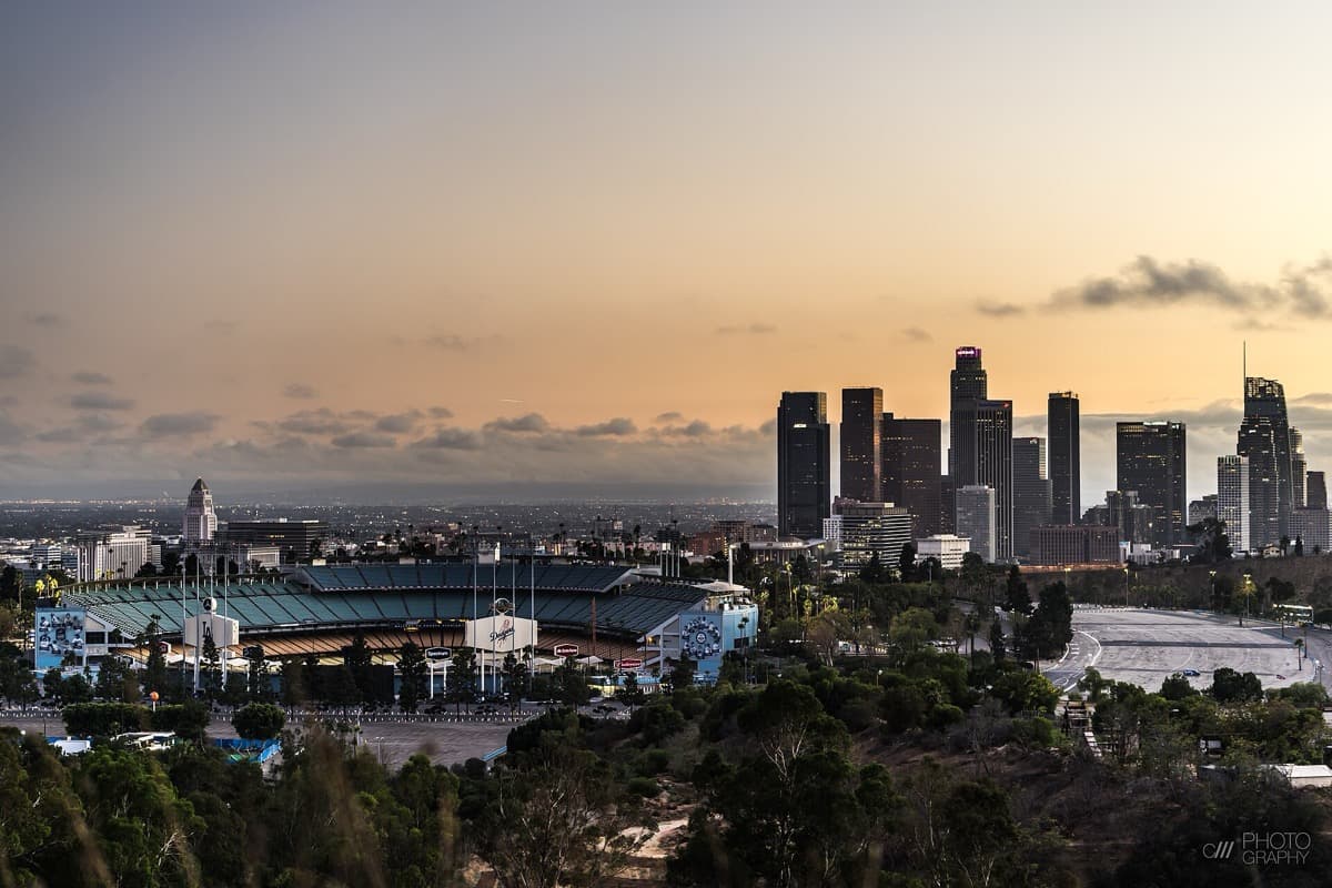 A large ballpark on a hill with city towers in the distance