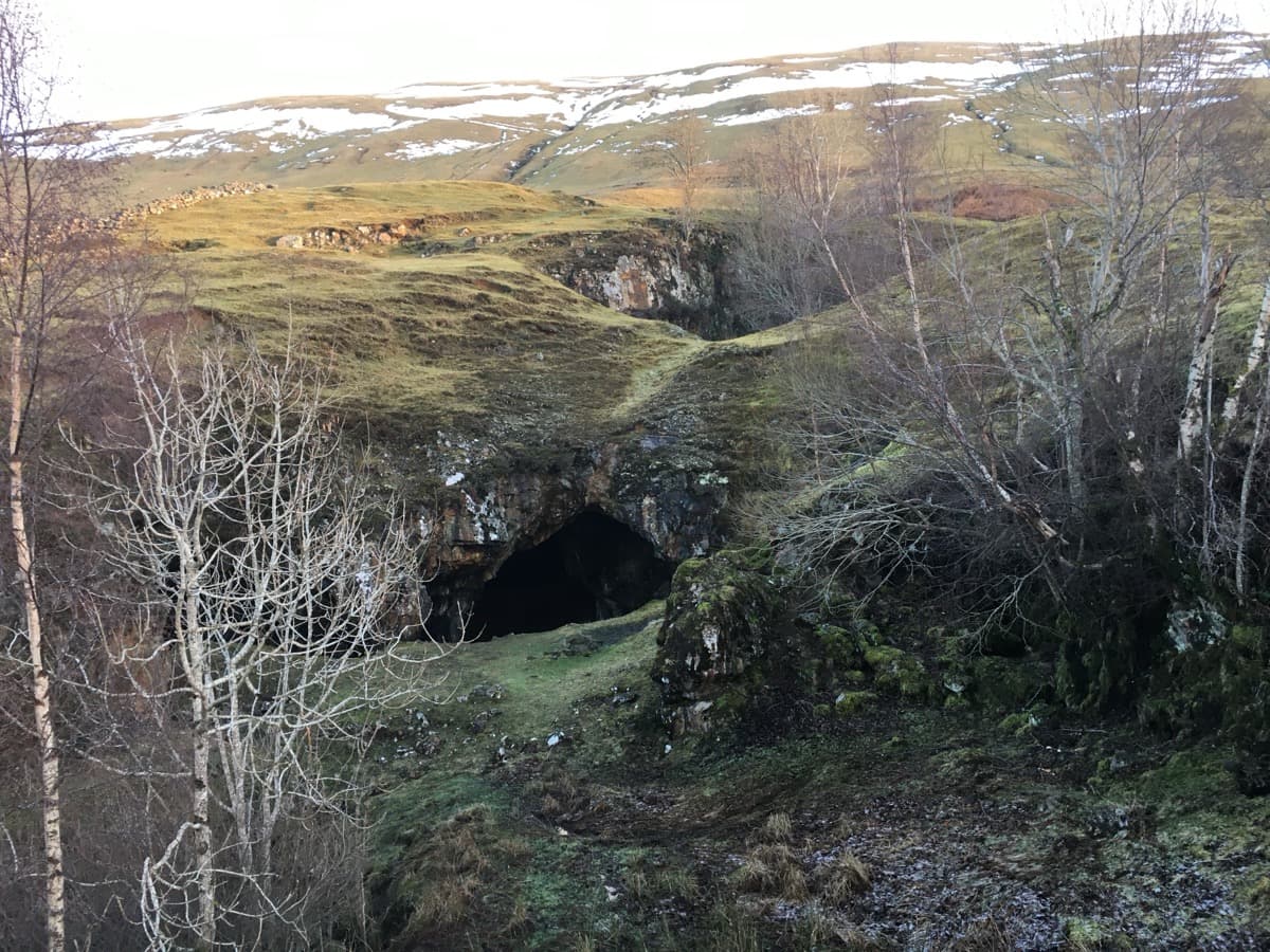 Stone ruins and a dark mine opening in a hillside at Tomnadashan.