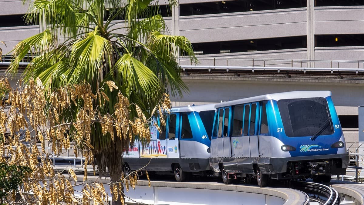 A two-car driverless train on an elevated track beside towers