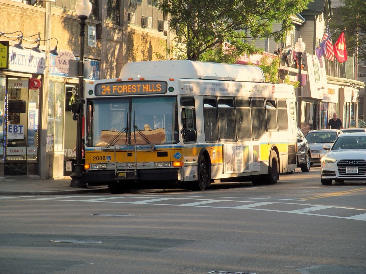 A bus stopped in a village-style square with shops
