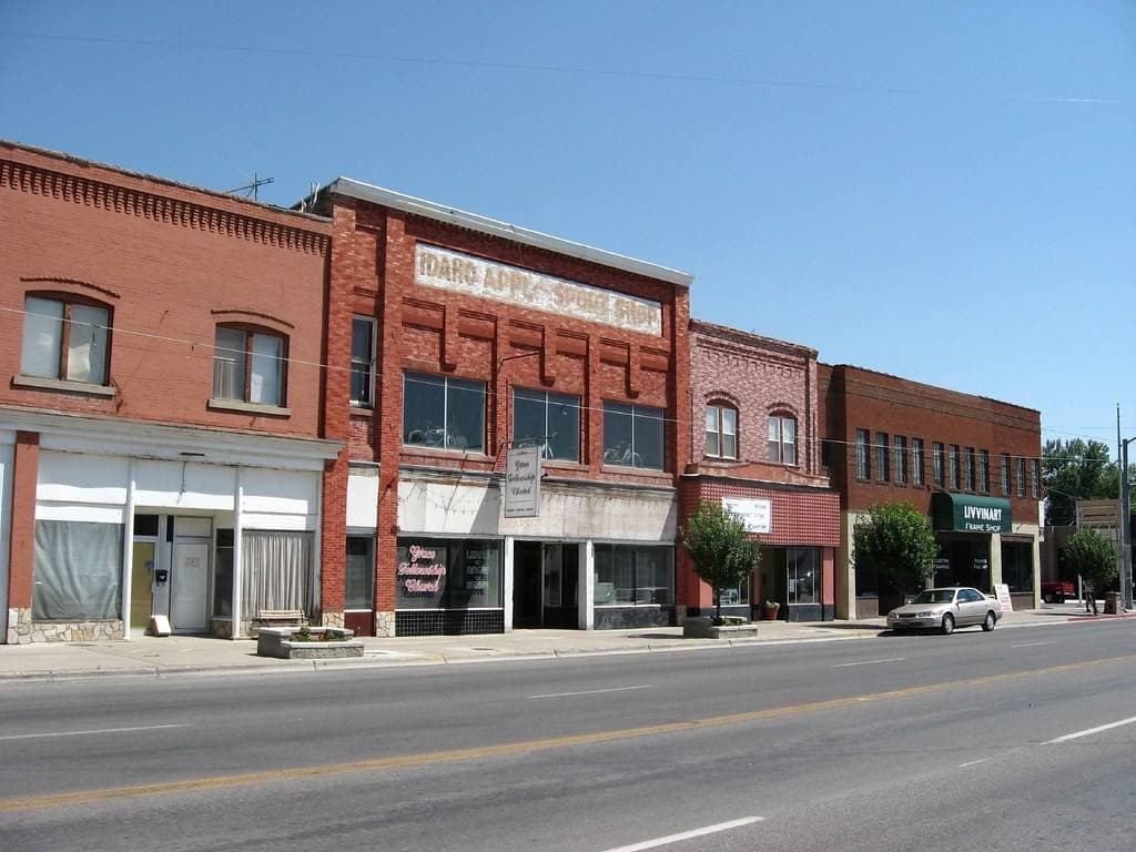 A row of old red-brick two-storey shop buildings on a sunny street