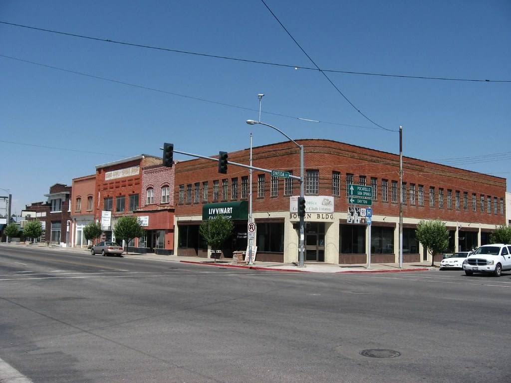 A brick corner block at a crossroads with traffic lights and green route signs
