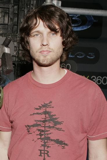 Jon Heder, tall and lean, with shaggy hair, in a red T-shirt