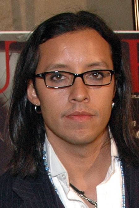 Efren Ramirez with long dark hair and rectangular glasses