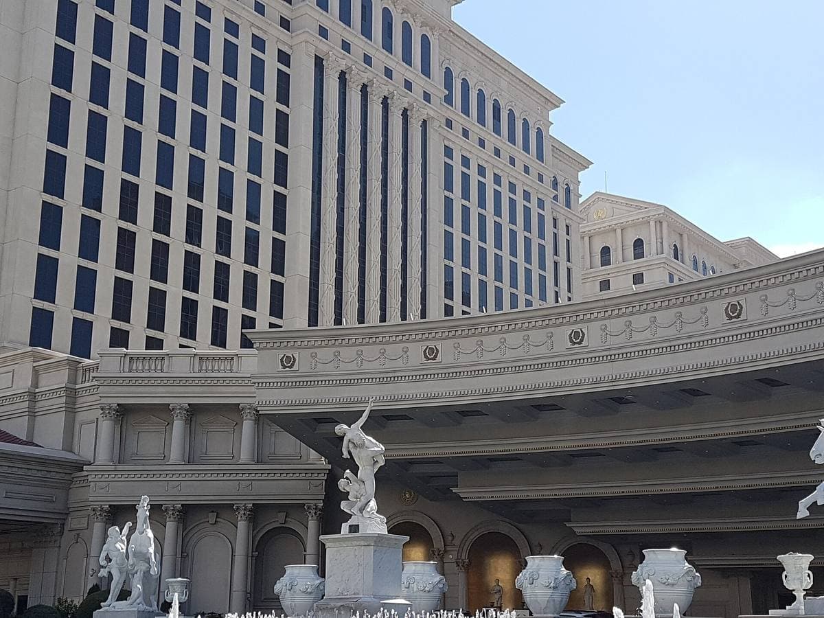 White classical statues and colonnades in front of a curved hotel tower