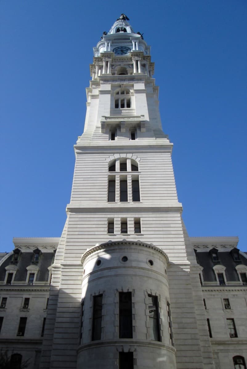 The carved stone courtyard of a large Victorian city hall, with its clock tower rising behind