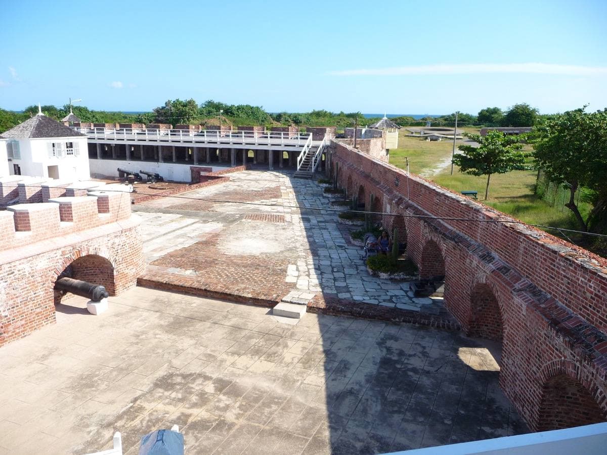 A brick rampart with cannon and a white building, seen from above on a sunny day
