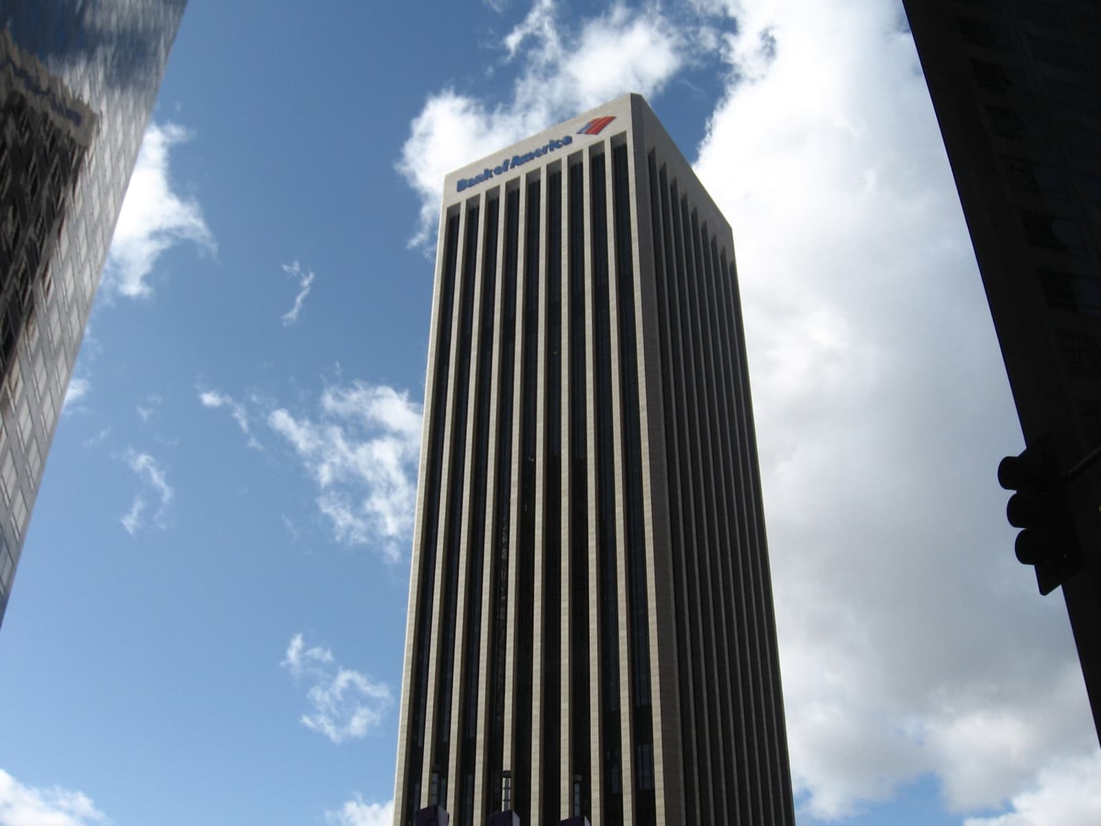 A dark striped skyscraper against a blue sky with clouds