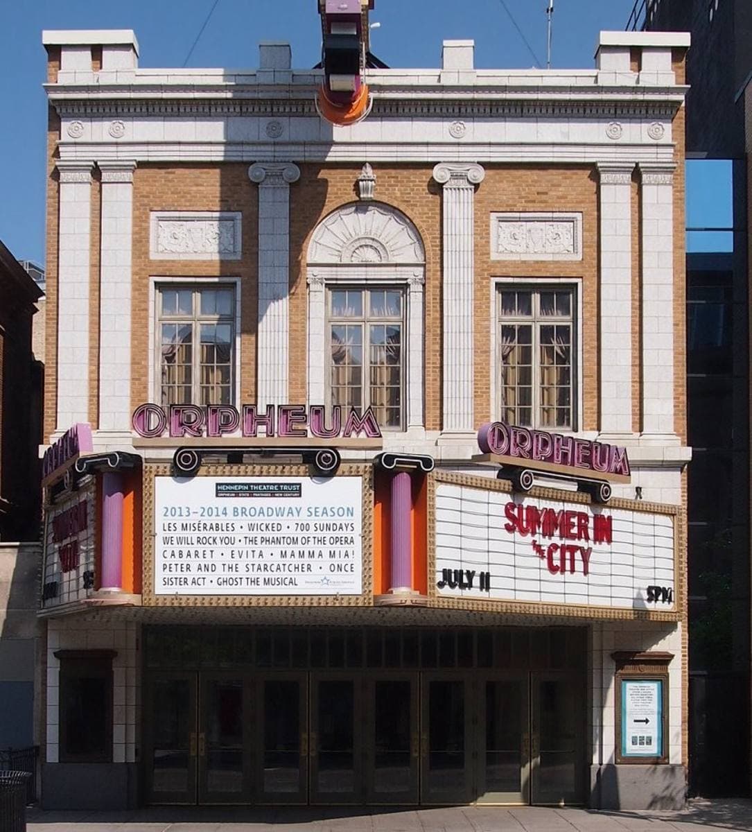 A pale brick theatre front with a pink-lettered Orpheum marquee
