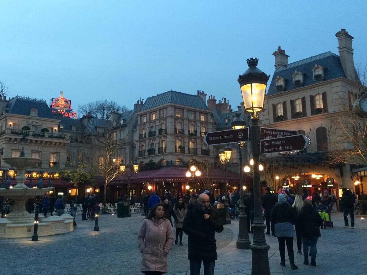 A Parisian-style restaurant frontage with a sign and awnings, set in a theme-park plaza
