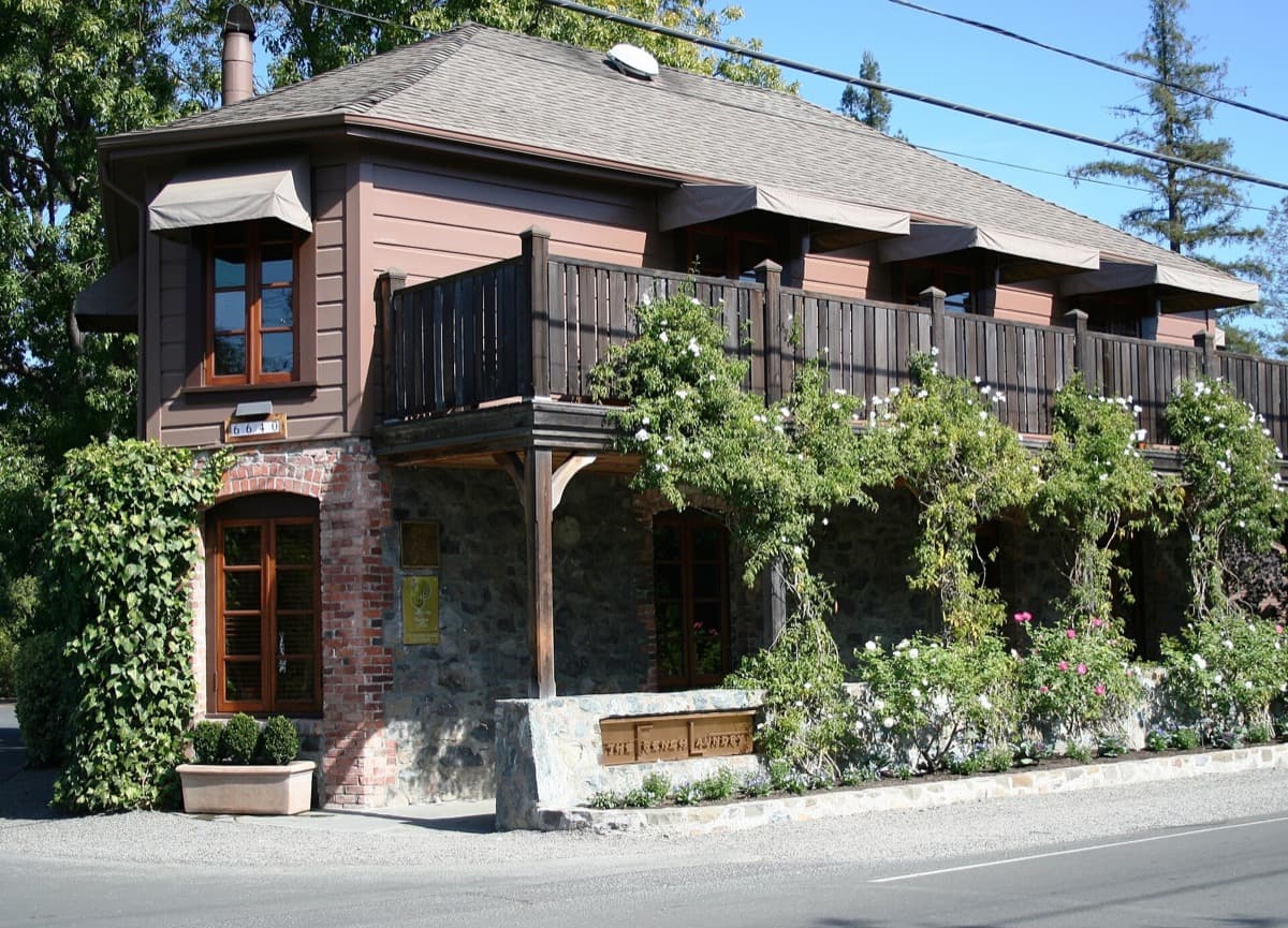 A two-storey stone cottage restaurant behind a garden of flowers