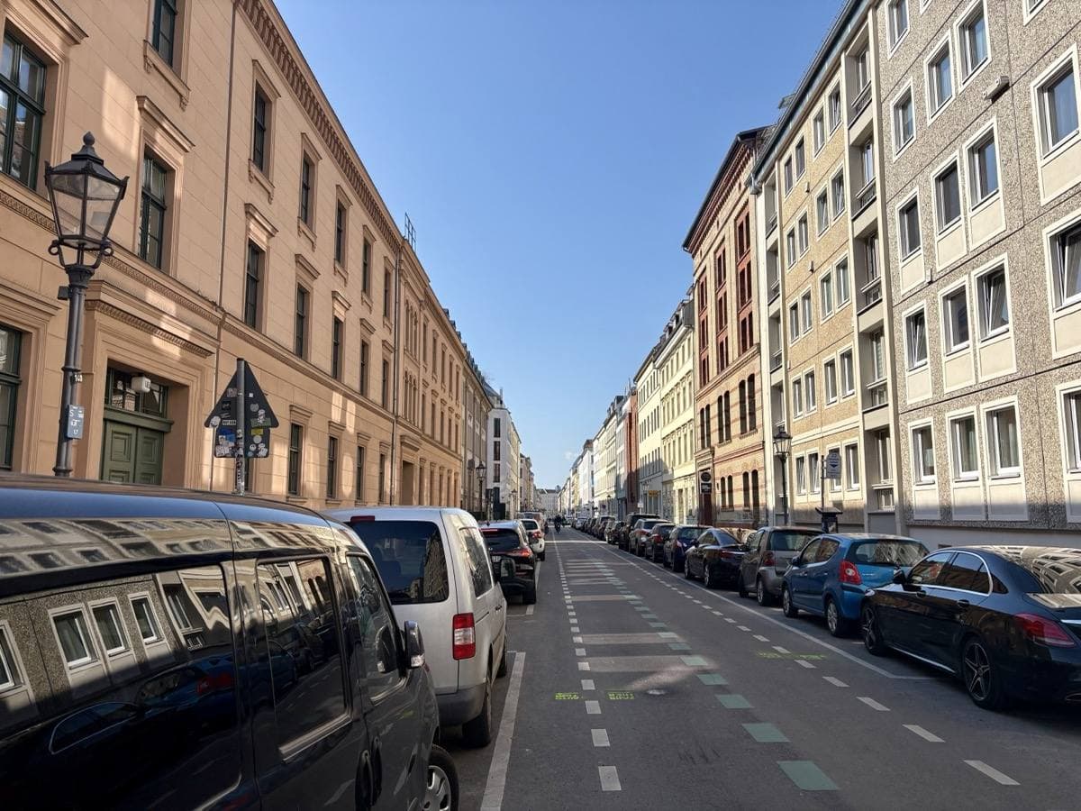 A long straight street of tall plastered houses under a blue sky