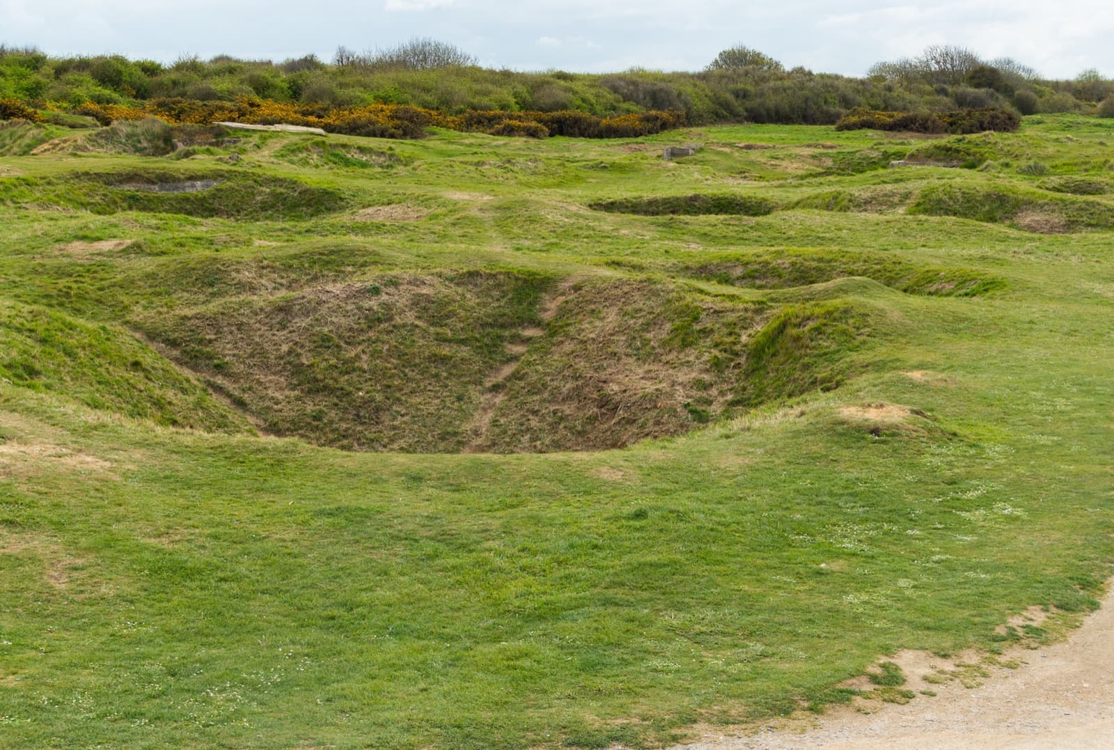 Deep grassy craters across a clifftop headland