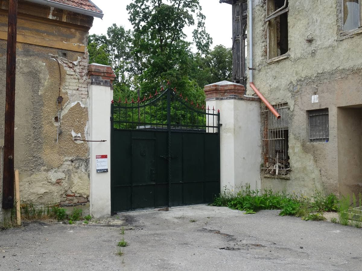 An iron gate between old factory buildings