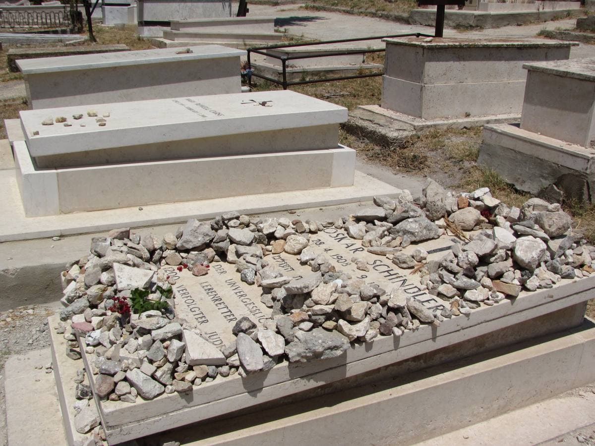 A stone grave slab heaped with pebbles among other pale tombs