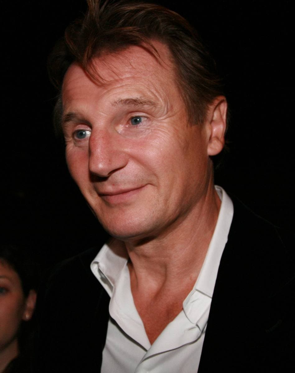 Liam Neeson in a dark jacket, looking to one side