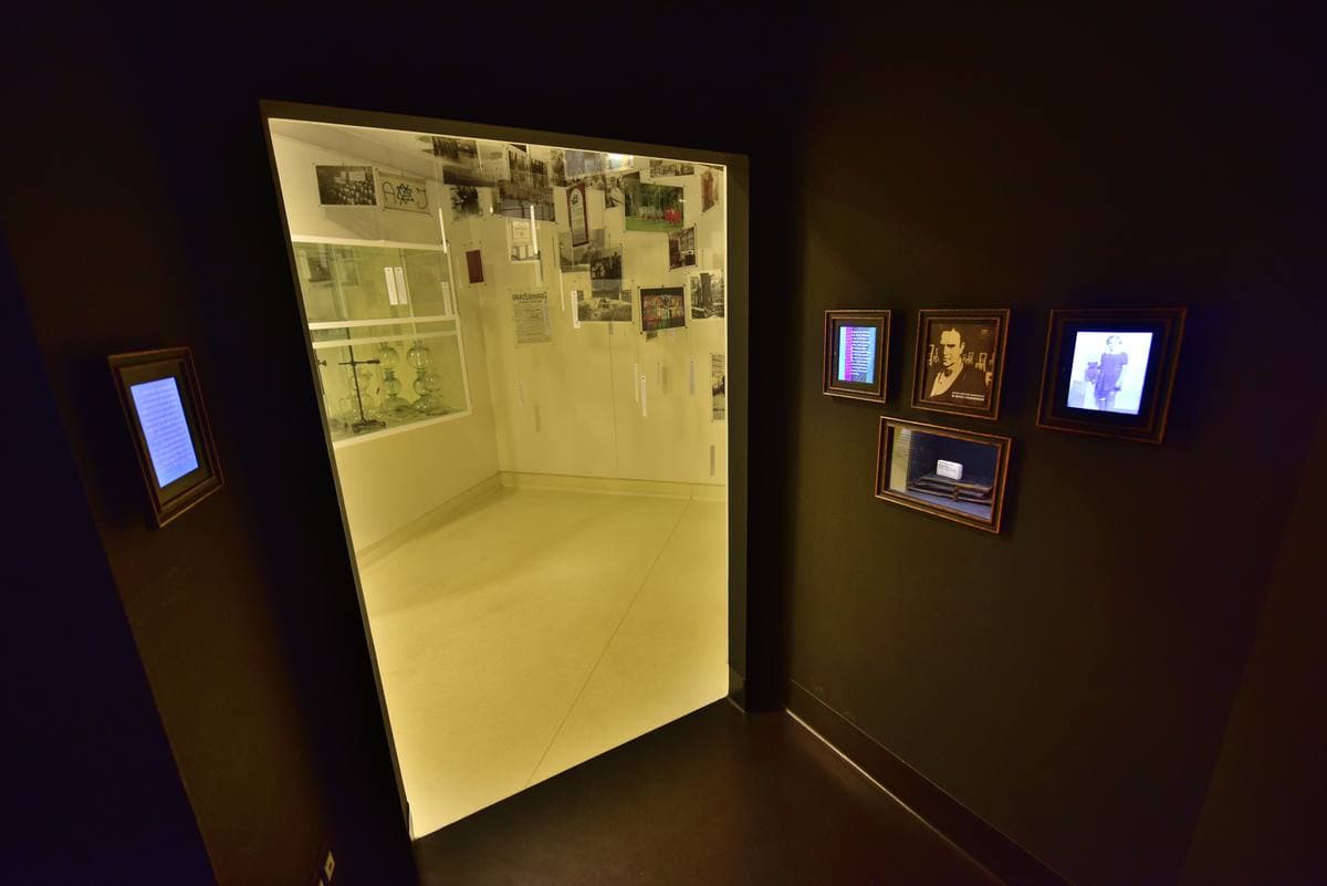 A dark exhibition room with a lit glass case of photographs