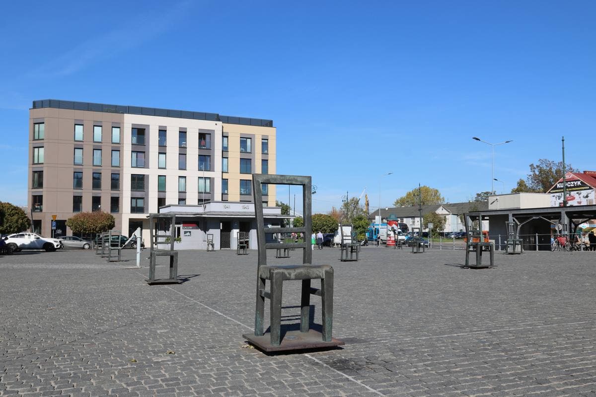 Large bronze chairs standing apart on an open paved square