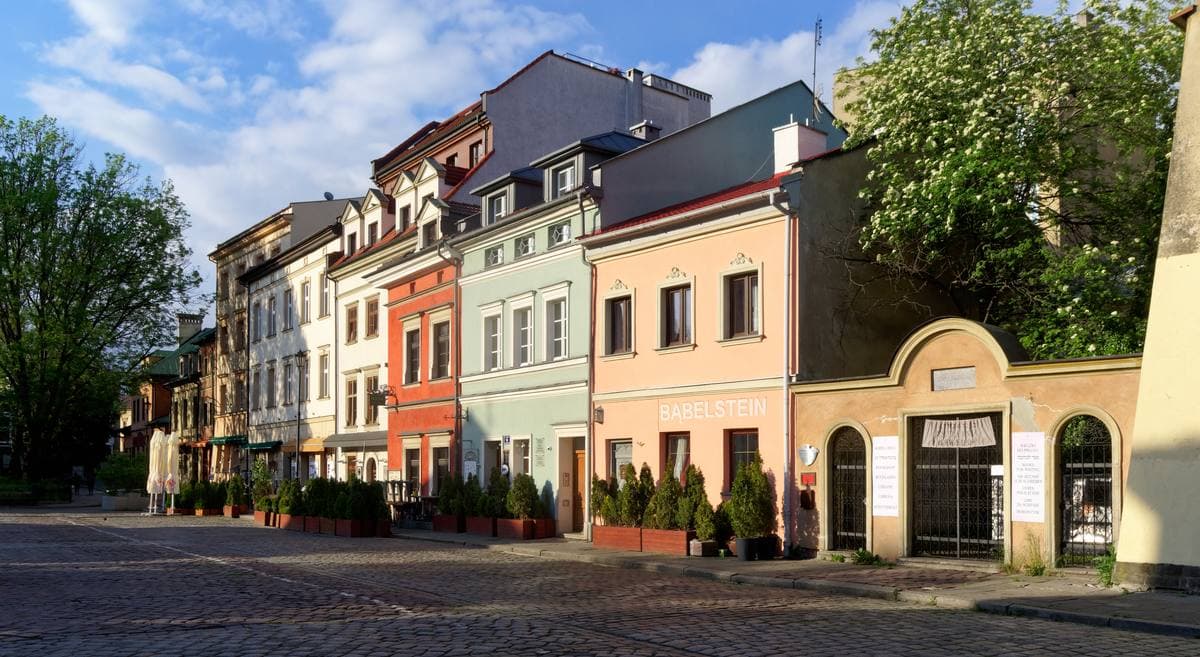 A wide cobbled street of low old houses under a blue sky