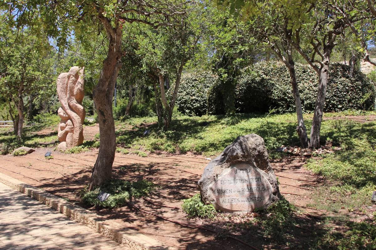 A shaded path among trees with stone plaques at their feet