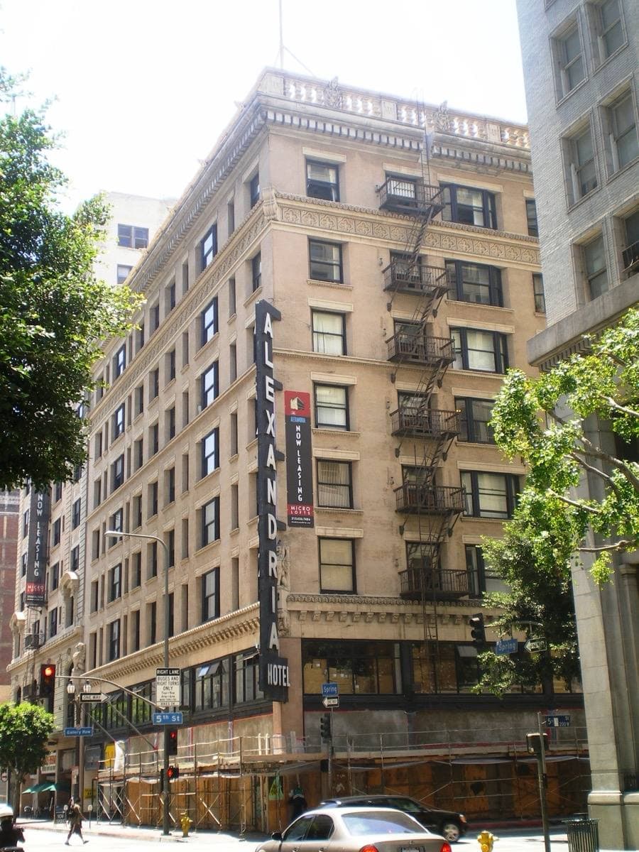 A tall brick hotel on a street corner with signs on its roof